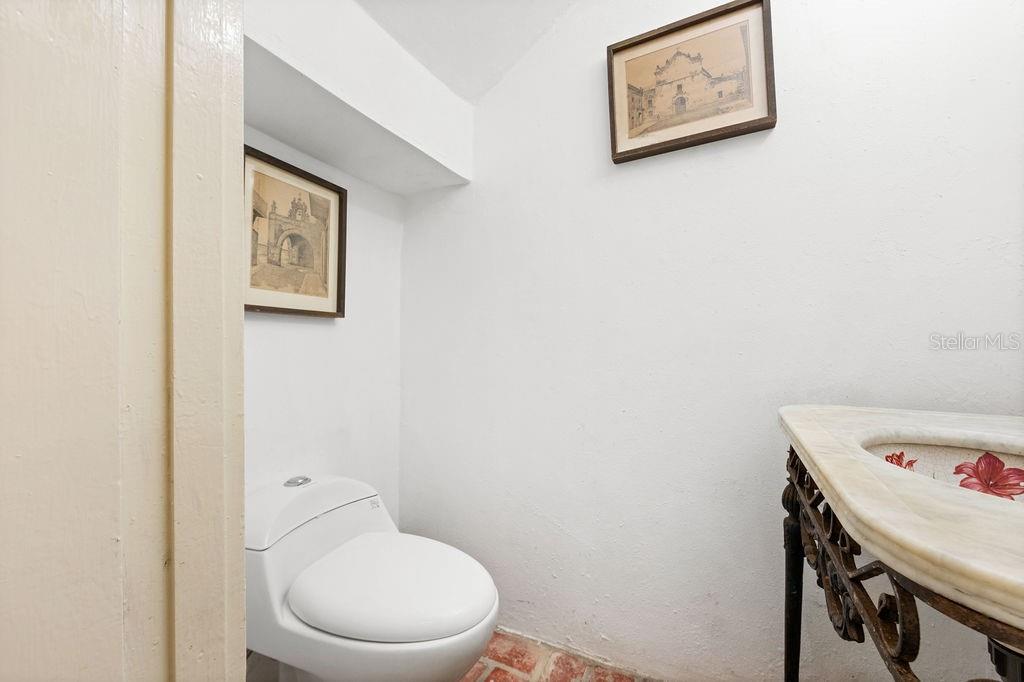 A small bathroom features a white toilet, a decorative sink, and two framed wall pictures — 50 SAN FRANCISCO ST, SAN JUAN, PR