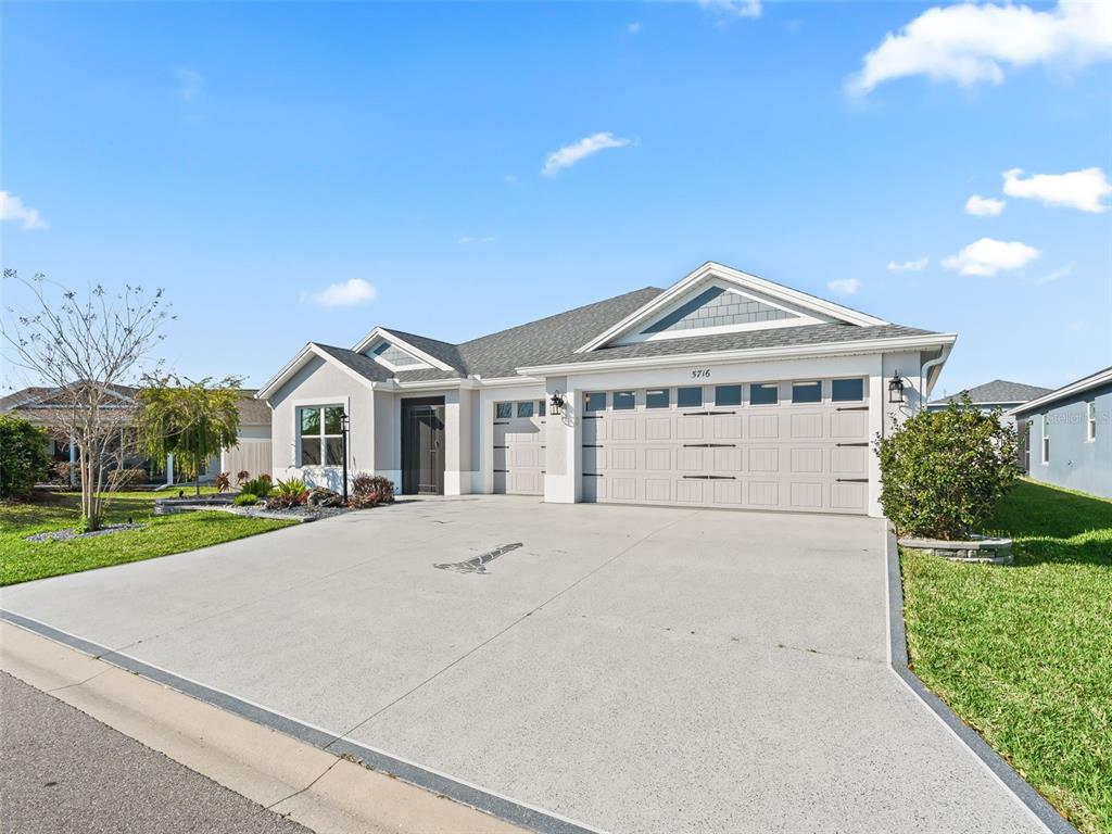 A single-story house with a gray exterior, a three-car garage, and a concrete driveway — 5716 MELVIN DRIVE, THE VILLAGES, FL