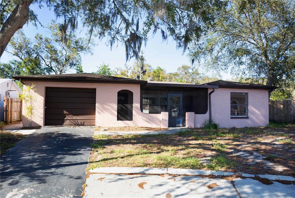 A single-story pink house with a brown garage door and a screened-in front porch — 9939 WOODRIDGE COURT, PORT RICHEY, FL