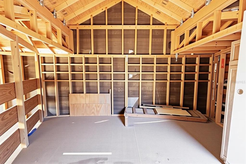 An unfinished interior space with exposed wood framing, plywood walls, and a vaulted ceiling — 9939 WOODRIDGE COURT, PORT RICHEY, FL