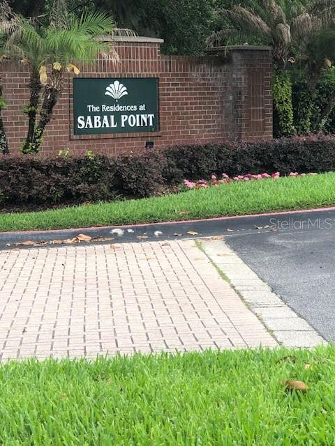 A brick wall features a sign for The Residences at Sabal Point near a road — 413 SUMMIT RIDGE PLACE UNIT 305, LONGWOOD, FL