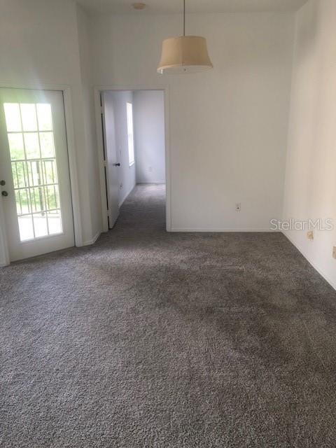 A carpeted room features a glass door, a pendant light, and an open doorway — 413 SUMMIT RIDGE PLACE UNIT 305, LONGWOOD, FL