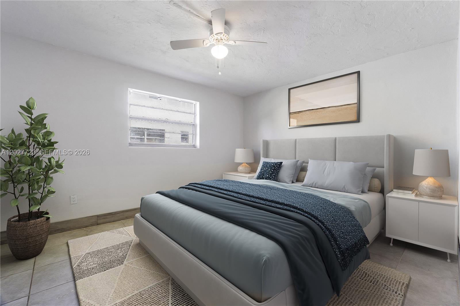 A bedroom features a bed with blue bedding, a ceiling fan, and a potted plant — 332 SW 3rd St # 5, Belle Glade FL 33430, BELLE GLADE, FL