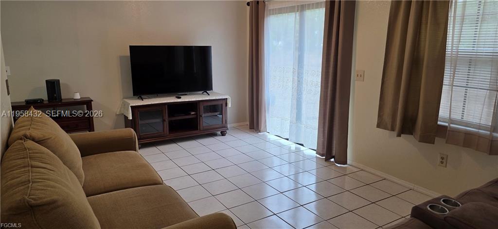 A living room features a tan sofa, a television on a wooden stand, and tile flooring — 5036 E Tradewinds Cir, La Belle FL 33935, LA BELLE, FL