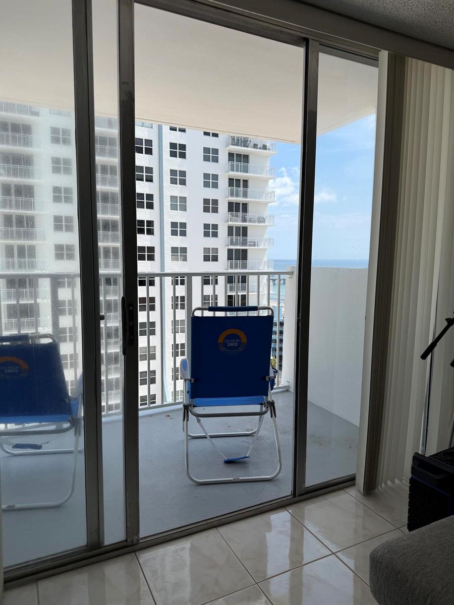 A balcony with two blue folding chairs overlooks a neighboring high-rise building and the ocean — 111 Briny Avenue # 1405, Pompano Beach FL 33062, POMPANO BEACH, FL