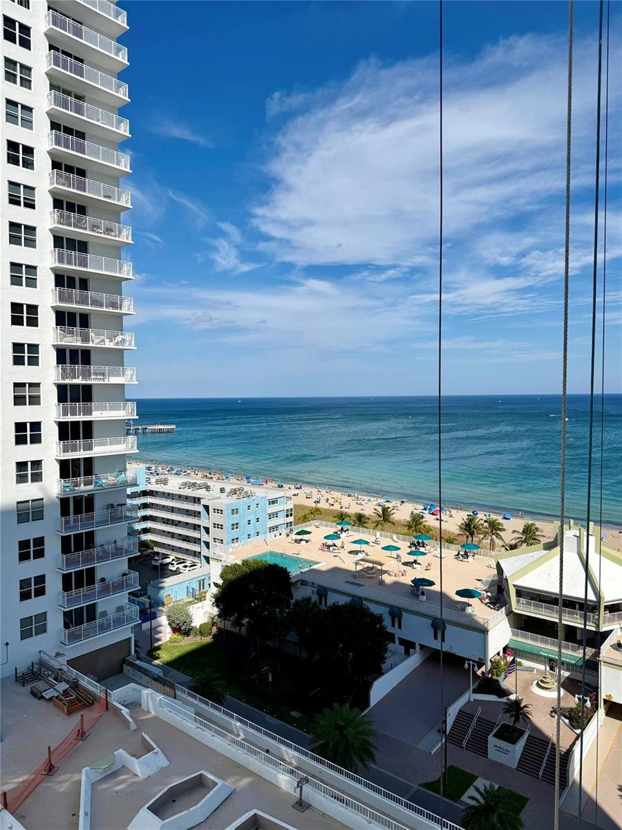 A high-angle view shows a beach, ocean, swimming pool, and a tall residential building — 111 Briny Avenue # 1405, Pompano Beach FL 33062, POMPANO BEACH, FL