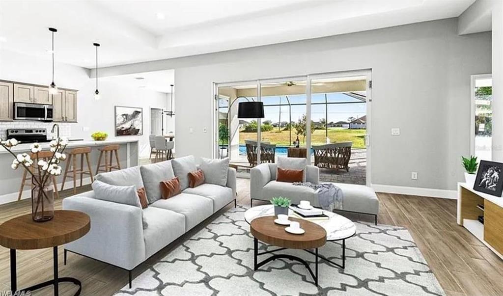 A modern living room with gray sofas, a patterned rug, and a view of a pool — 2153 NW 18TH AVENUE, CAPE CORAL, FL