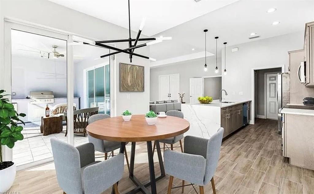 A dining area with a round table and gray chairs opens to a covered patio — 2153 NW 18TH AVENUE, CAPE CORAL, FL
