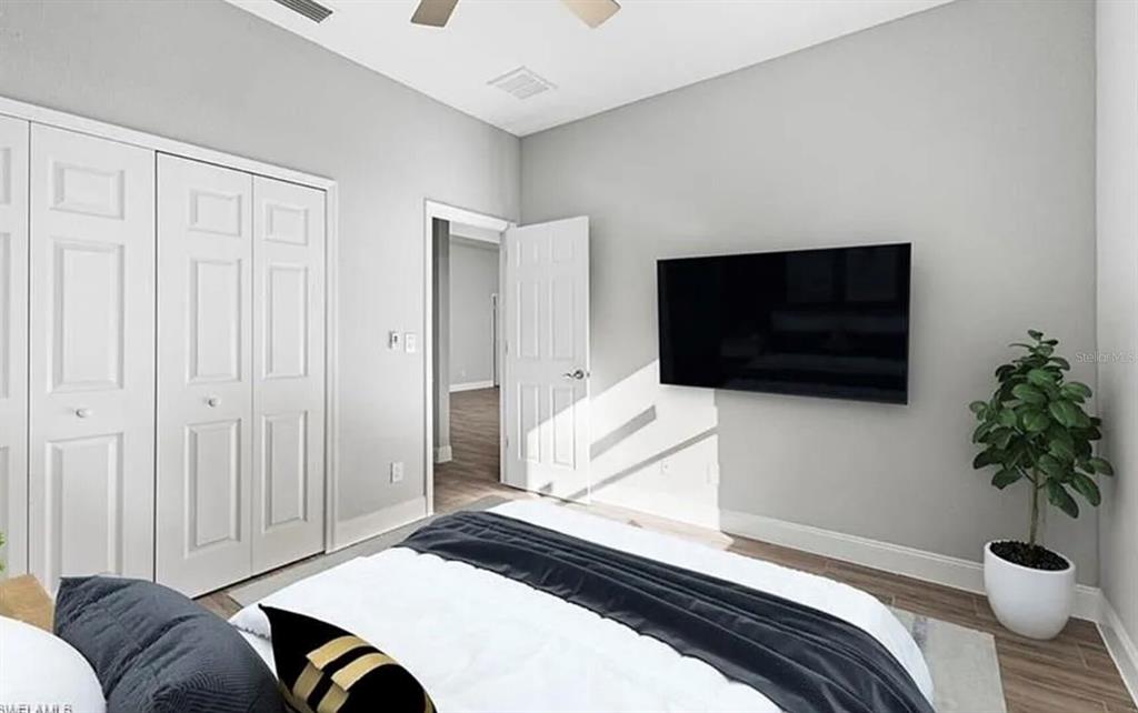 A bedroom features light gray walls, a wall-mounted television, a bed, and white closet doors — 2153 NW 18TH AVENUE, CAPE CORAL, FL
