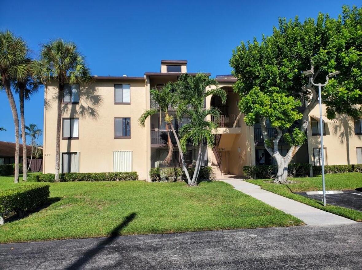 A three-story tan apartment building with palm trees and a sidewalk in front — 629 Sea Pine Way # A1, FL 33415, FL
