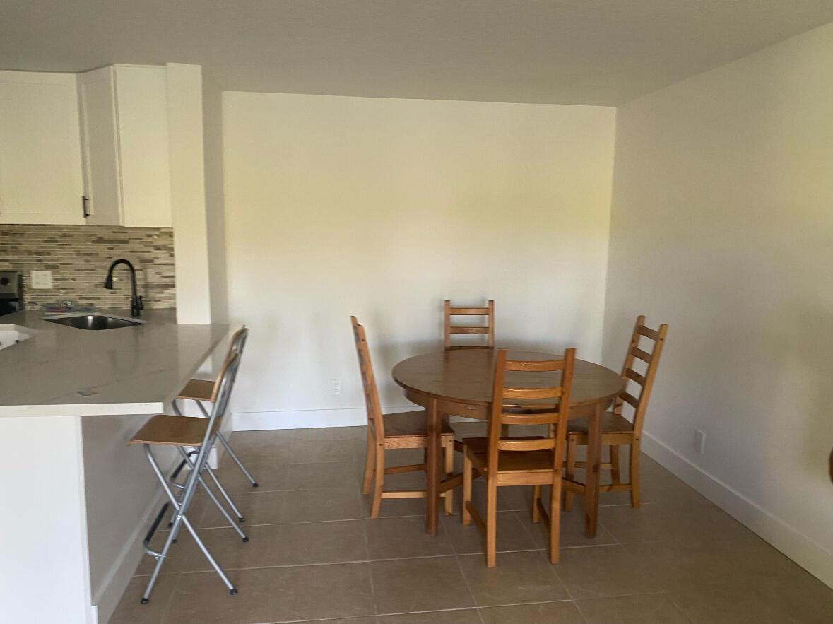 A dining area with a round wooden table and chairs adjacent to a kitchen island — 629 Sea Pine Way # A1, FL 33415, FL