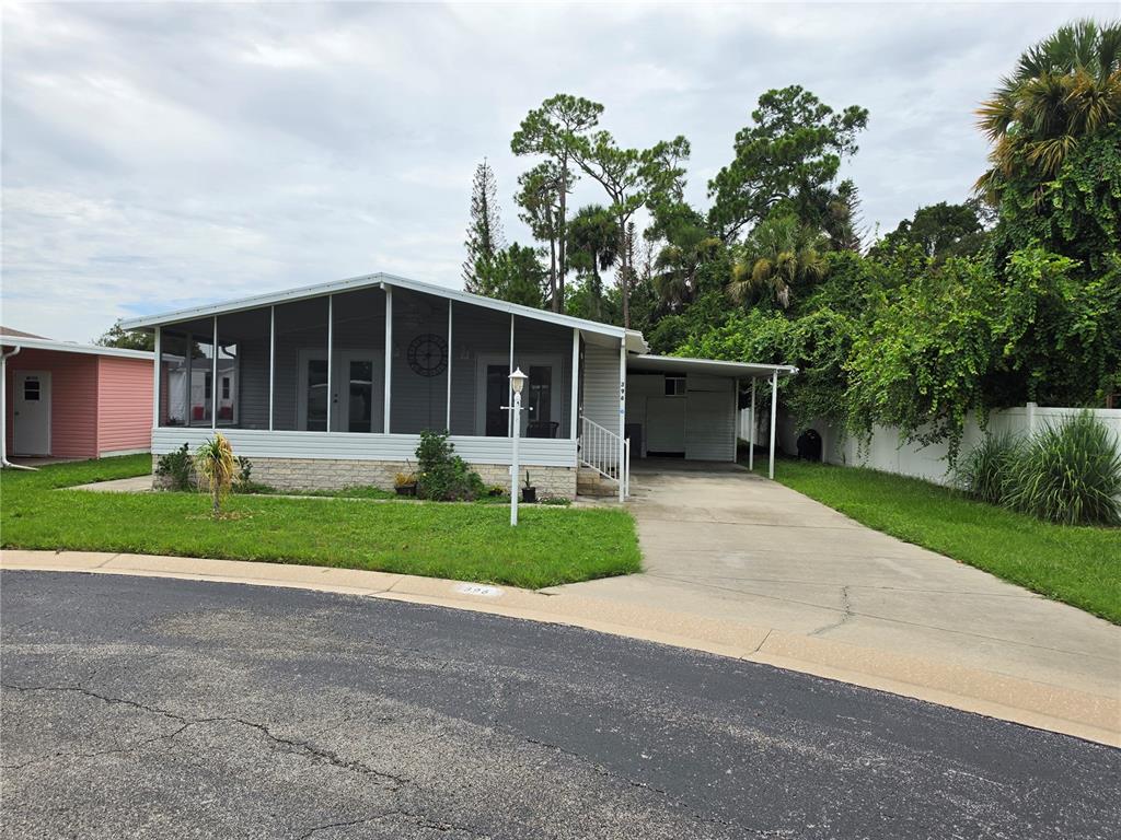 A single-story manufactured home with a screened-in porch, a concrete driveway, and a carport — 1000 WALKER STREET UNIT 396, HOLLY HILL, FL