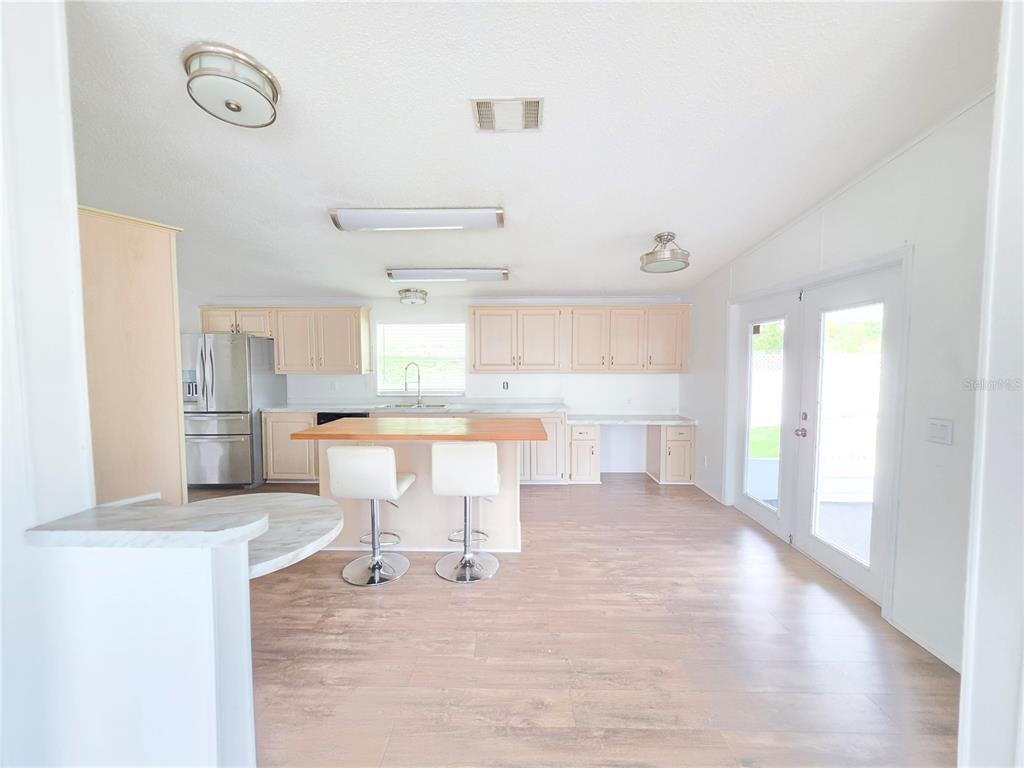 A living room with wood-look flooring, a ceiling fan, and French doors leading outside — 1000 WALKER STREET UNIT 396, HOLLY HILL, FL