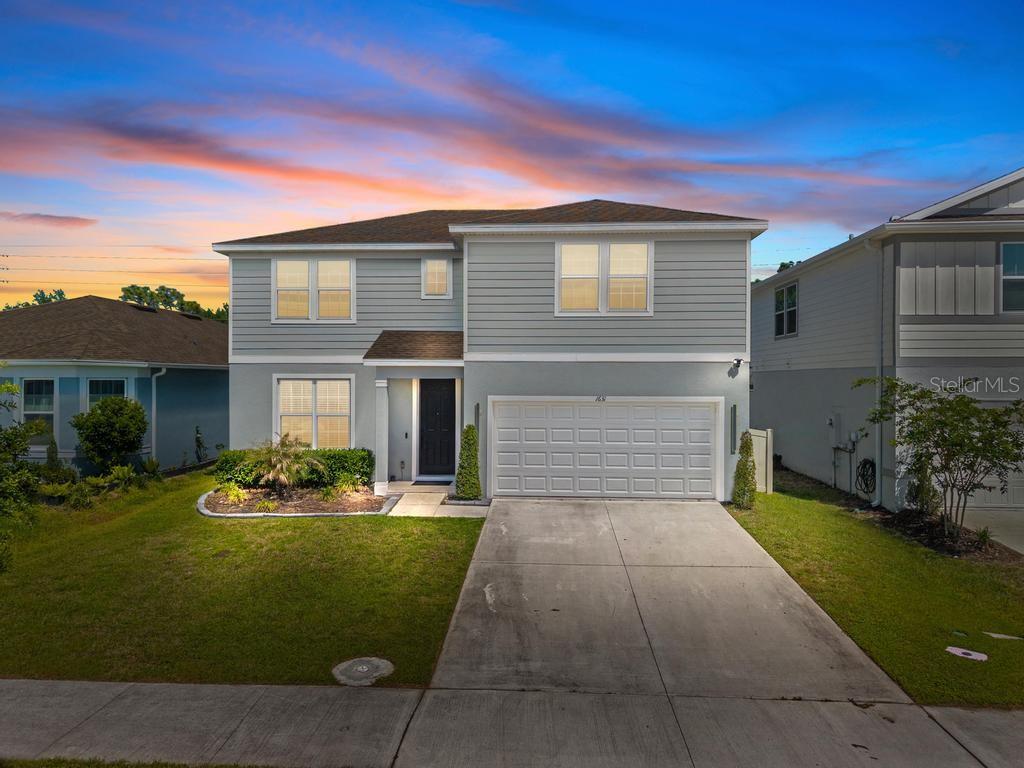 A two-story suburban house with light gray siding, a two-car garage, and a concrete driveway — 1631 GROVELINE ROAD, ST CLOUD, FL