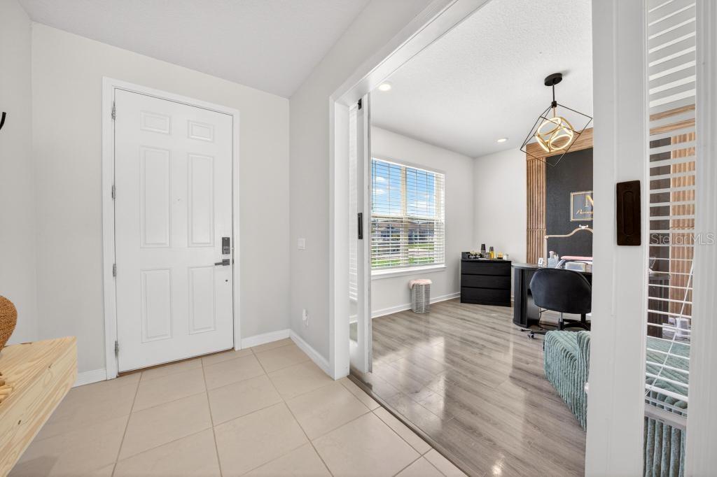 A tiled entryway leads to a home office with wood flooring and sliding glass doors — 1631 GROVELINE ROAD, ST CLOUD, FL