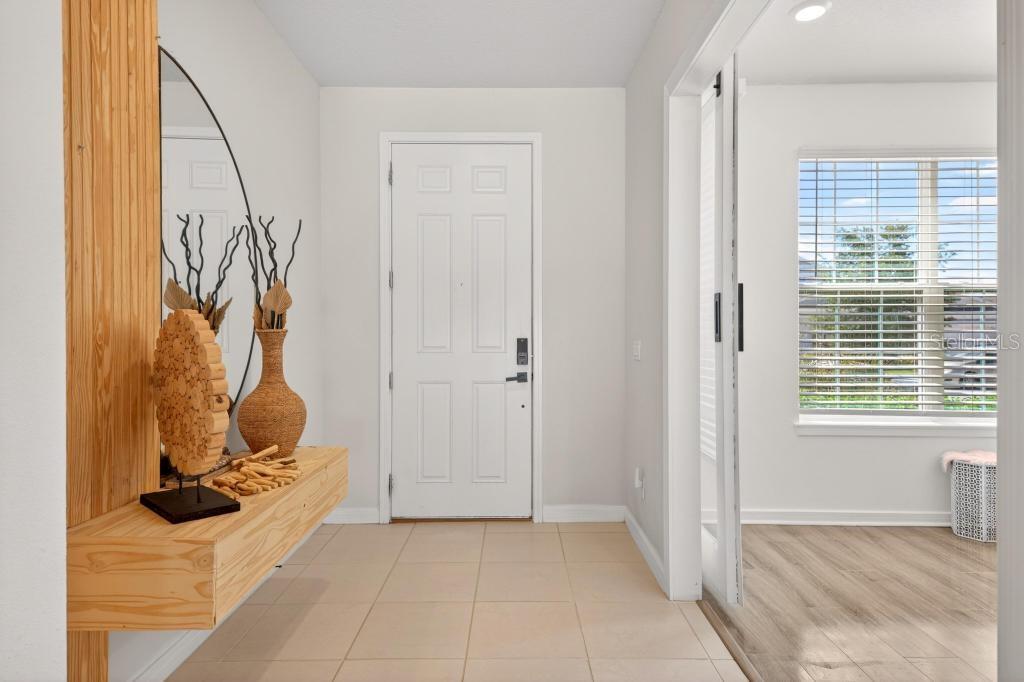 An entryway features a light wood console table, a round mirror, and a white front door — 1631 GROVELINE ROAD, ST CLOUD, FL