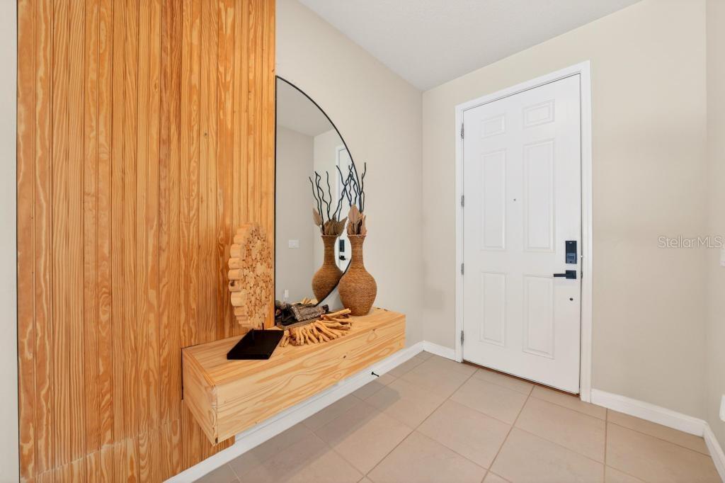 An entryway features a floating wood console, a vertical wood-paneled wall, and a large mirror — 1631 GROVELINE ROAD, ST CLOUD, FL