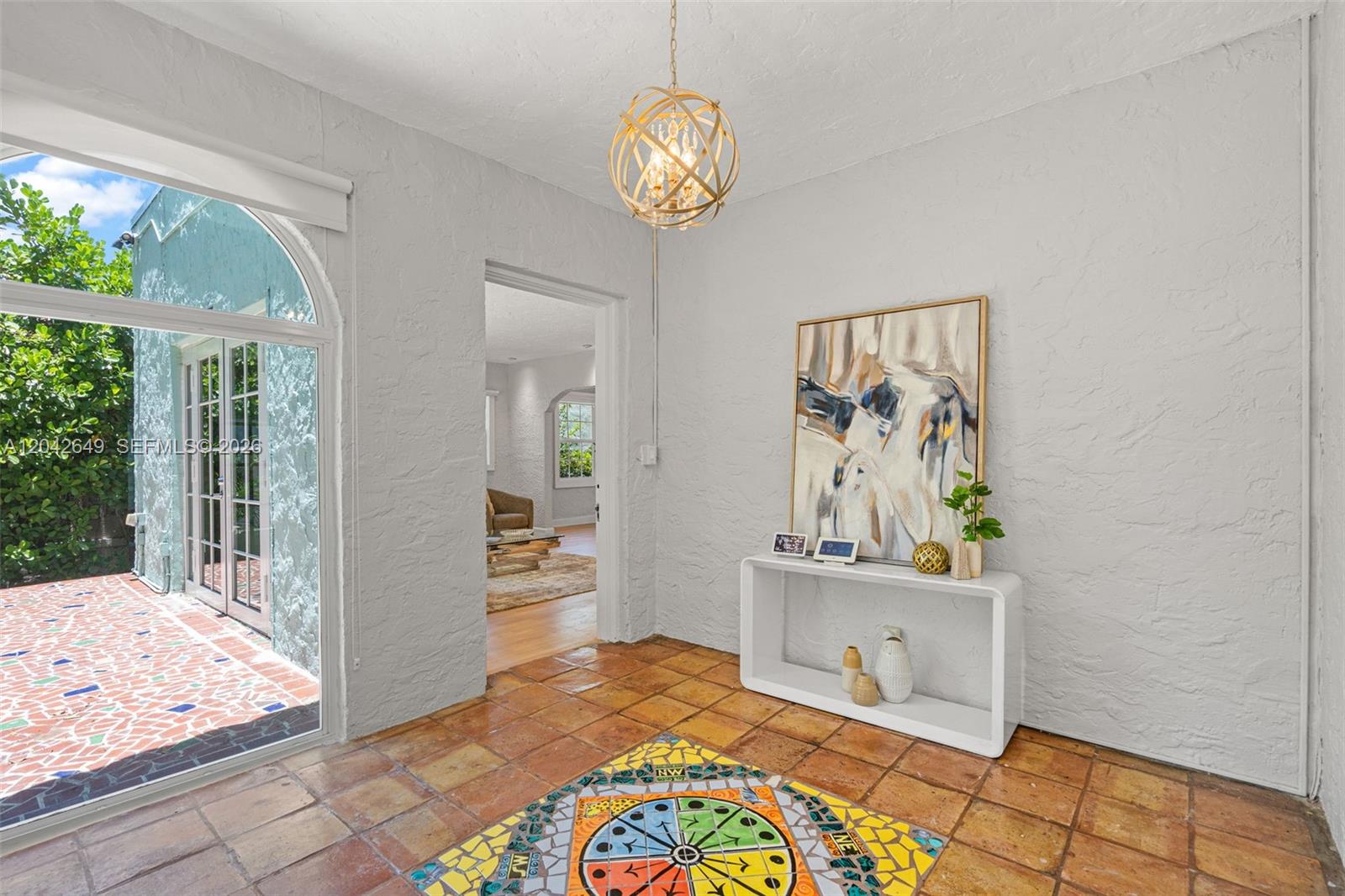 A sunlit entryway features terracotta tile flooring, a mosaic compass inlay, and a modern console table — 1209 La Mancha Ave, Coral Gables FL 33134, CORAL GABLES, FL