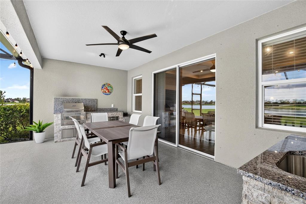 A covered outdoor patio features a dining set, built-in grill, sink, and views of water — 12313 NORA GRANT PLACE, RIVERVIEW, FL