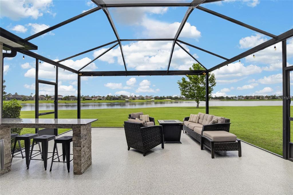 A screened-in patio features a stone-topped bar, outdoor seating, and a view of a lake — 12313 NORA GRANT PLACE, RIVERVIEW, FL