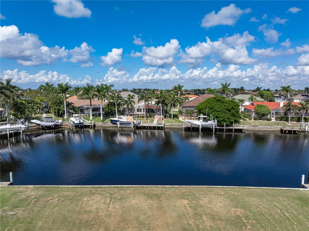 An aerial view shows a canal with several boats docked behind residential houses and palm trees — 452 VALLETTA COURT, PUNTA GORDA, FL