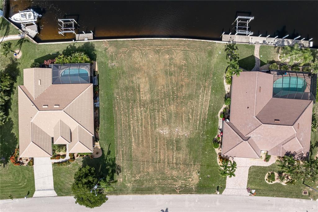 An aerial view shows a vacant residential lot situated between two houses along a canal — 452 VALLETTA COURT, PUNTA GORDA, FL
