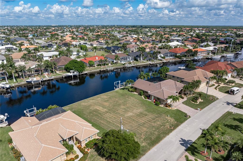 An aerial view shows a vacant waterfront lot situated between two houses along a canal — 452 VALLETTA COURT, PUNTA GORDA, FL