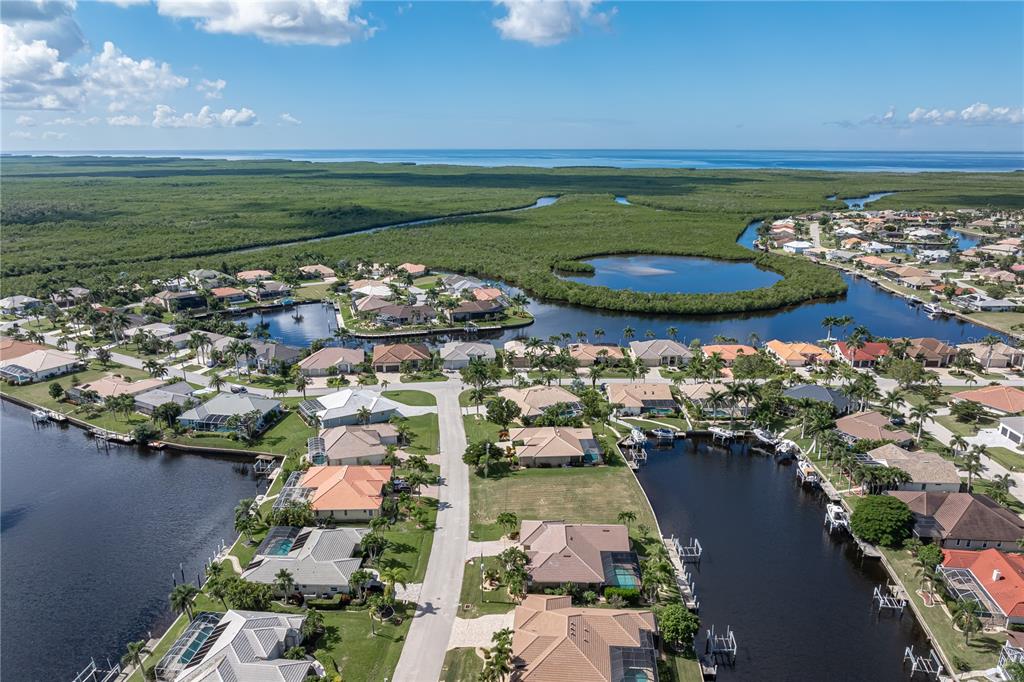 An aerial view of a waterfront residential neighborhood featuring canals, houses, and surrounding mangroves — 452 VALLETTA COURT, PUNTA GORDA, FL