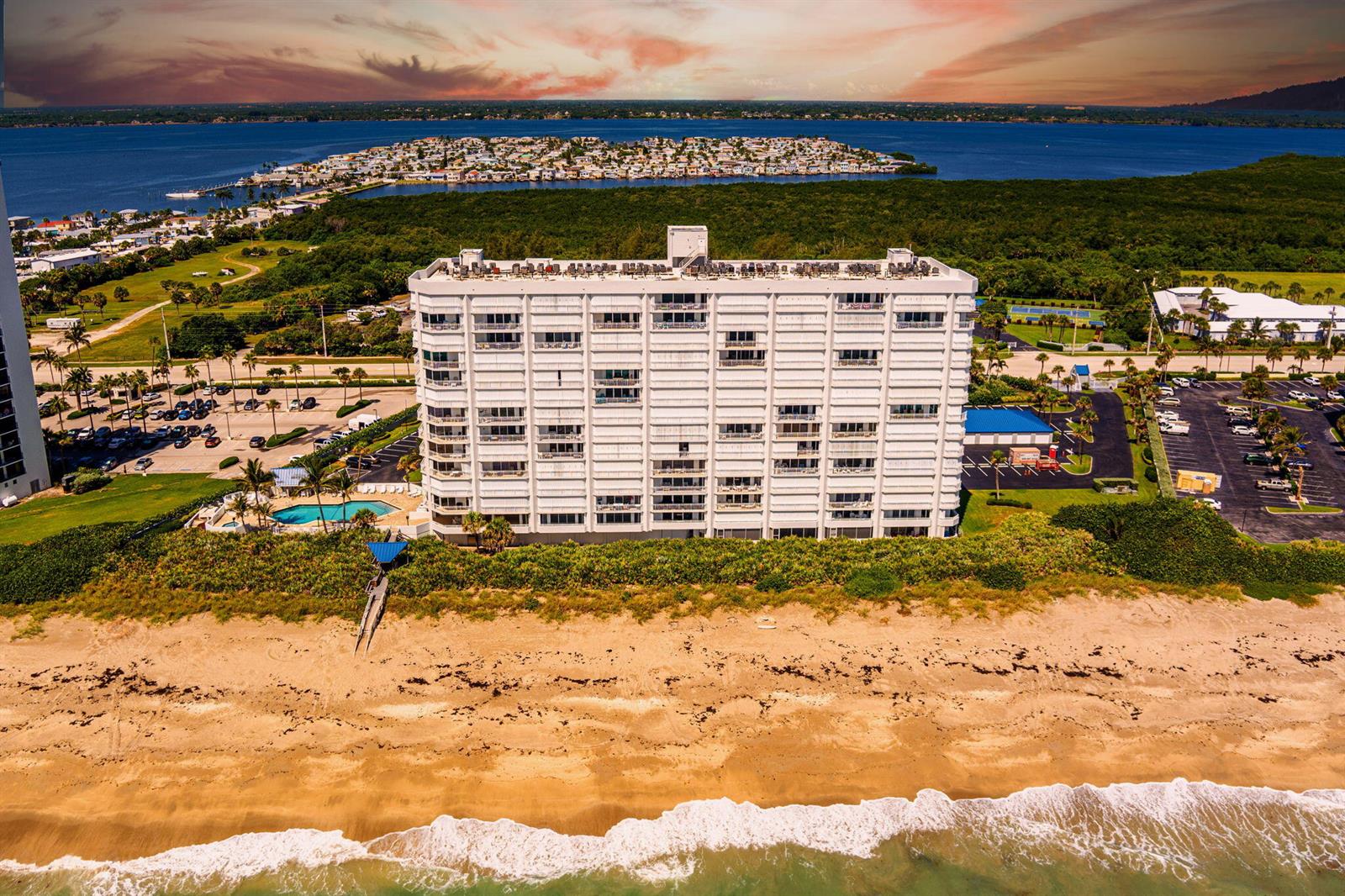 An aerial view of a white multi-story beachfront condominium building with a pool and parking — 9600 S Ocean Drive # 906, Jensen Beach FL 34957, JENSEN BEACH, FL
