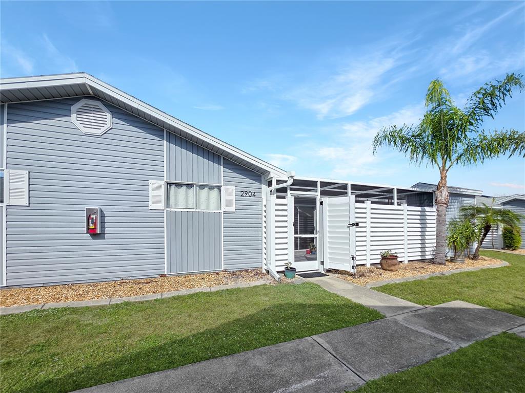 A light blue mobile home with a screened-in porch and a palm tree outside — 3300 LOVELAND BOULEVARD UNIT 2904, PORT CHARLOTTE, FL