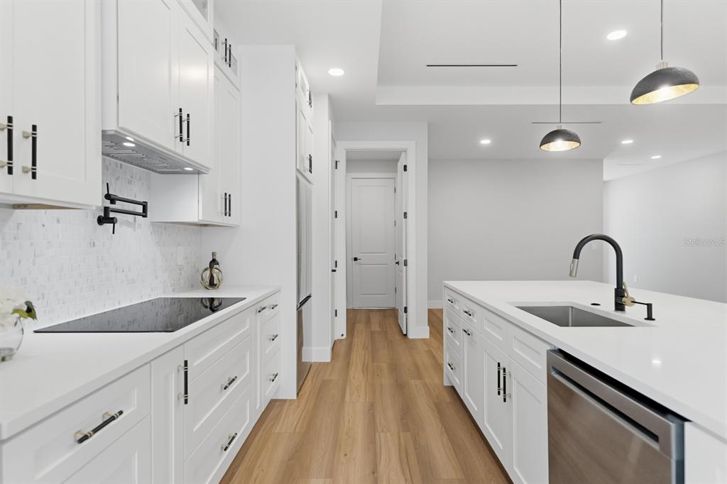 A modern white kitchen features a central island, stainless steel appliances, and light wood flooring — 64 HIGHLAND STREET, BROOKSVILLE, FL