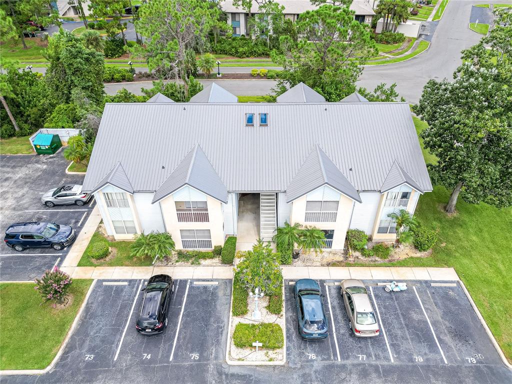 An aerial view shows a two-story apartment building with a metal roof and parking lot — 101 BENT TREE DRIVE UNIT 75, DAYTONA BEACH, FL