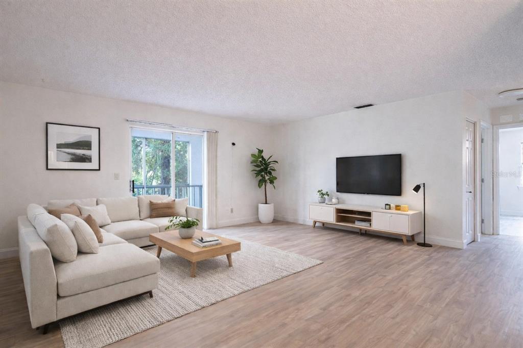A bright living room features a sectional sofa, a coffee table, and a wall-mounted television — 101 BENT TREE DRIVE UNIT 75, DAYTONA BEACH, FL