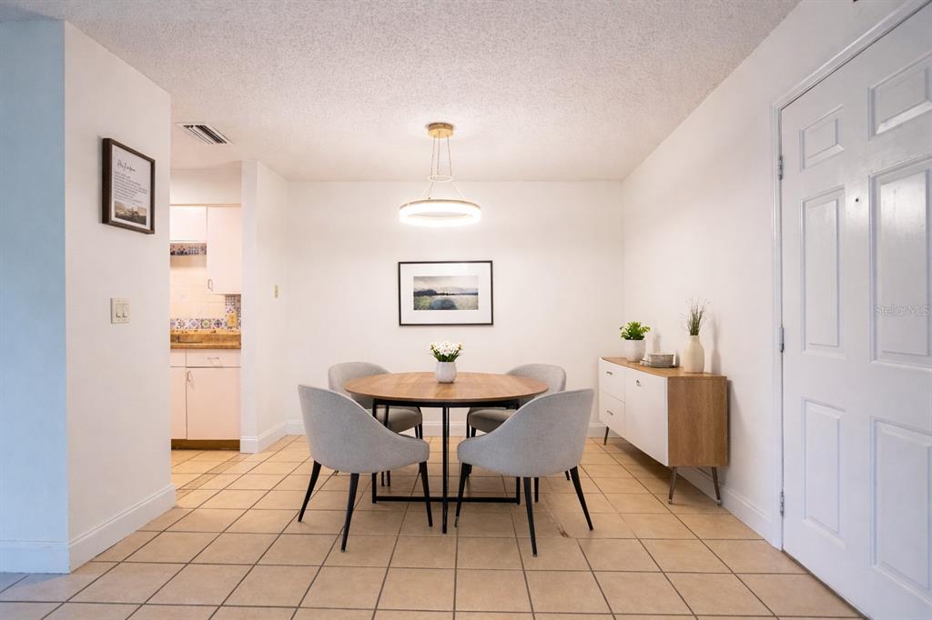 A dining area features a round wooden table, four gray chairs, and a modern light fixture — 101 BENT TREE DRIVE UNIT 75, DAYTONA BEACH, FL