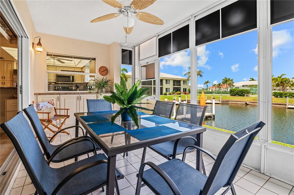 A sunroom features a dining set, tile flooring, and large windows overlooking a canal — 3640 BAL HARBOR BOULEVARD UNIT 112, PUNTA GORDA, FL