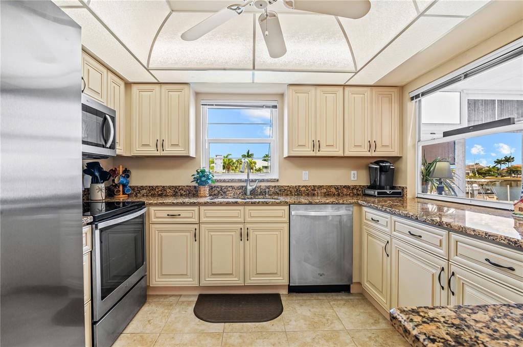 A kitchen with cream cabinets, granite countertops, stainless steel appliances, and a view of water — 3640 BAL HARBOR BOULEVARD UNIT 112, PUNTA GORDA, FL