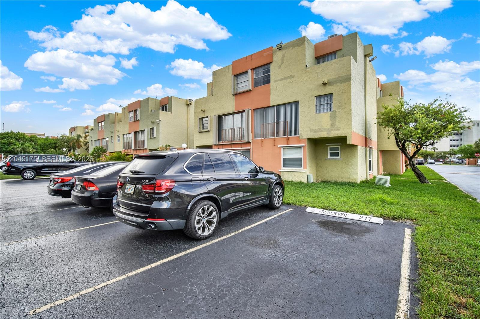 A multi-story apartment building with a parking lot in the foreground featuring reserved spaces — 9390 W Flagler St # 218F, Miami FL 33174, MIAMI, FL
