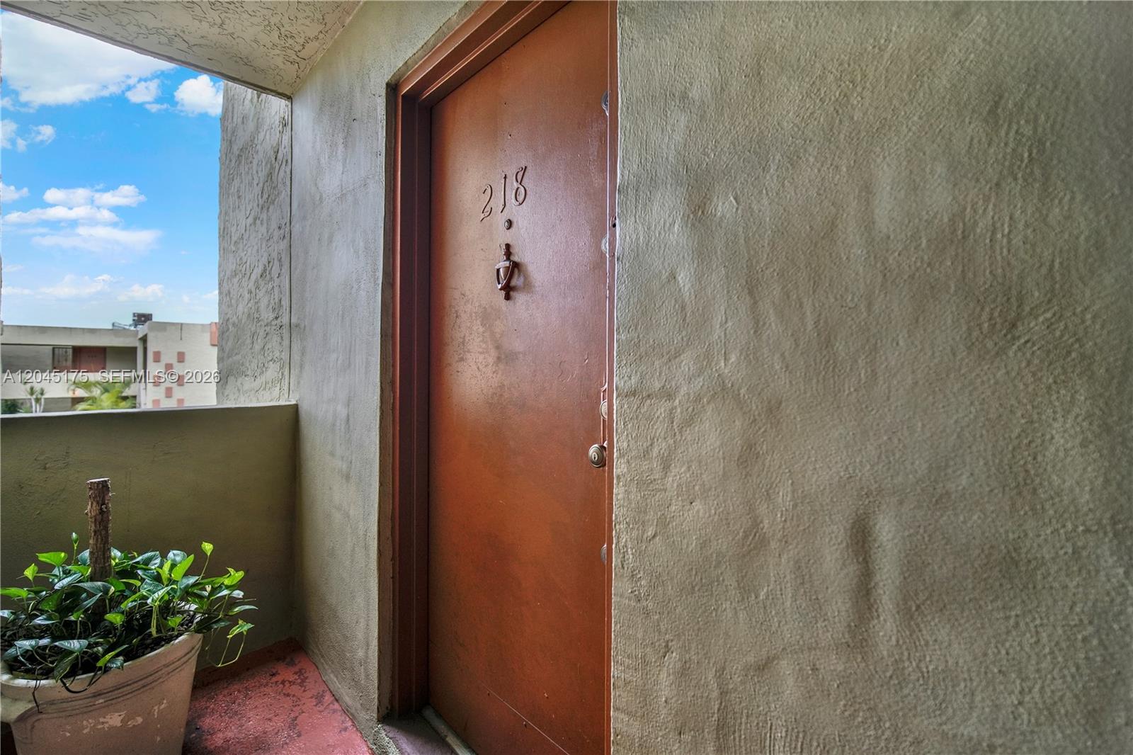 A brown apartment door with the number 218 is situated on an outdoor balcony — 9390 W Flagler St # 218F, Miami FL 33174, MIAMI, FL