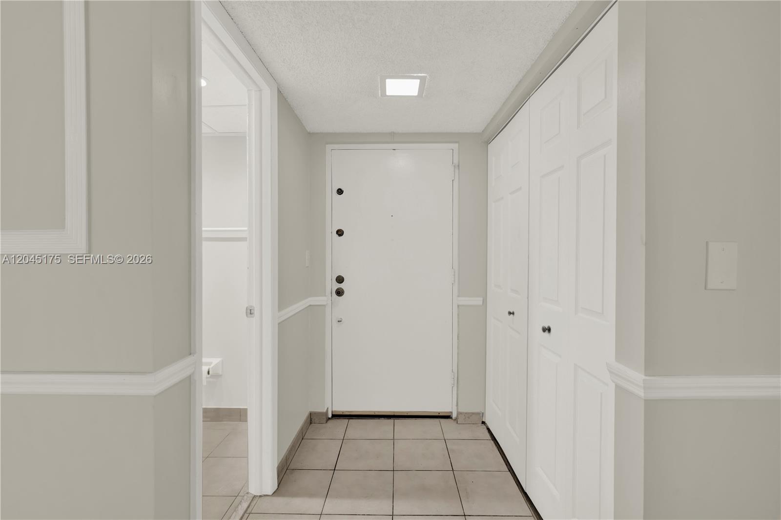 A tiled entryway features a white door, a closet with double doors, and a bathroom — 9390 W Flagler St # 218F, Miami FL 33174, MIAMI, FL