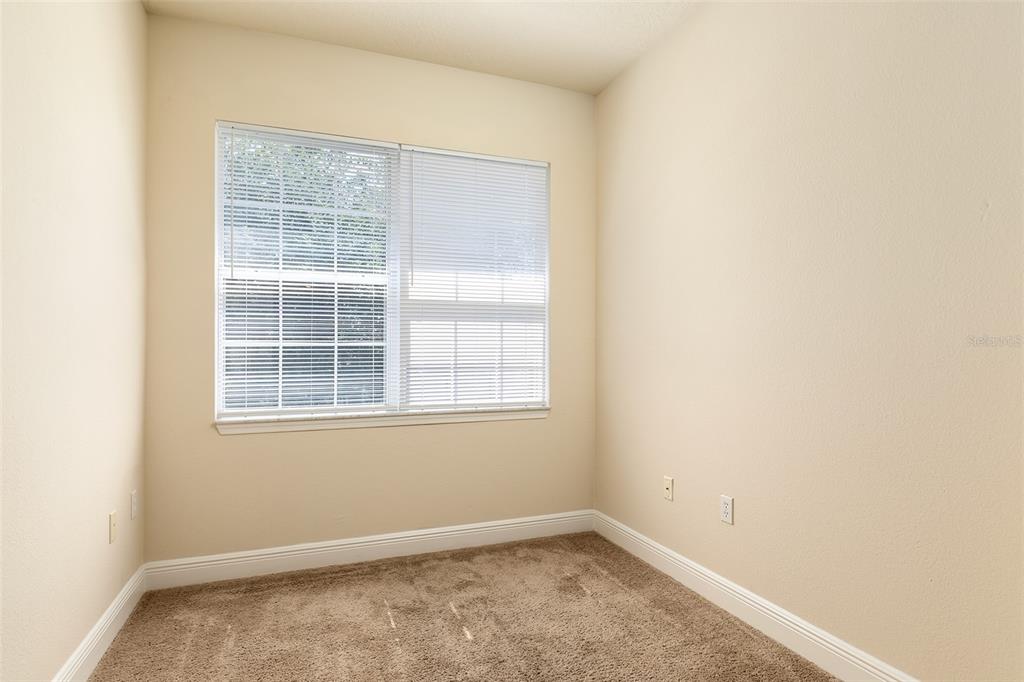 An empty room with beige walls, tan carpet, and a window with white blinds — 417 SOUTHERN PECAN CIRCLE UNIT 202, WINTER GARDEN, FL