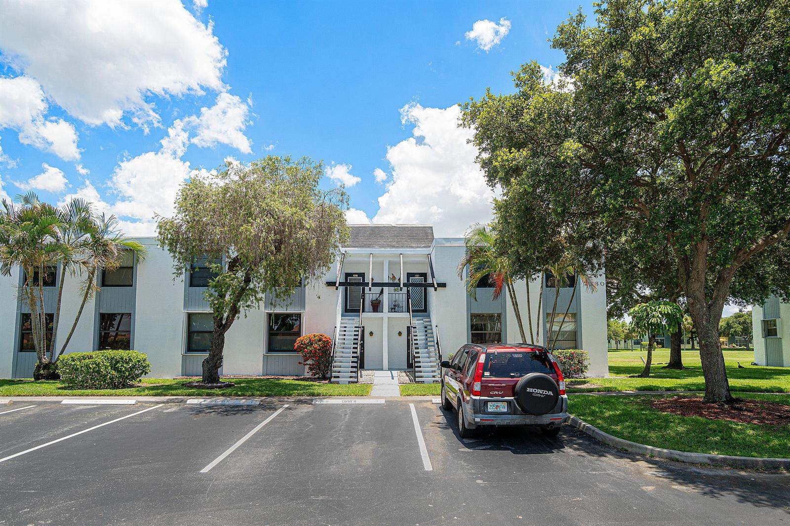 A two-story apartment building with white stucco walls, exterior staircases, and a parked red SUV — 7380 NW 18th Street # 108, Margate FL 33063, MARGATE, FL