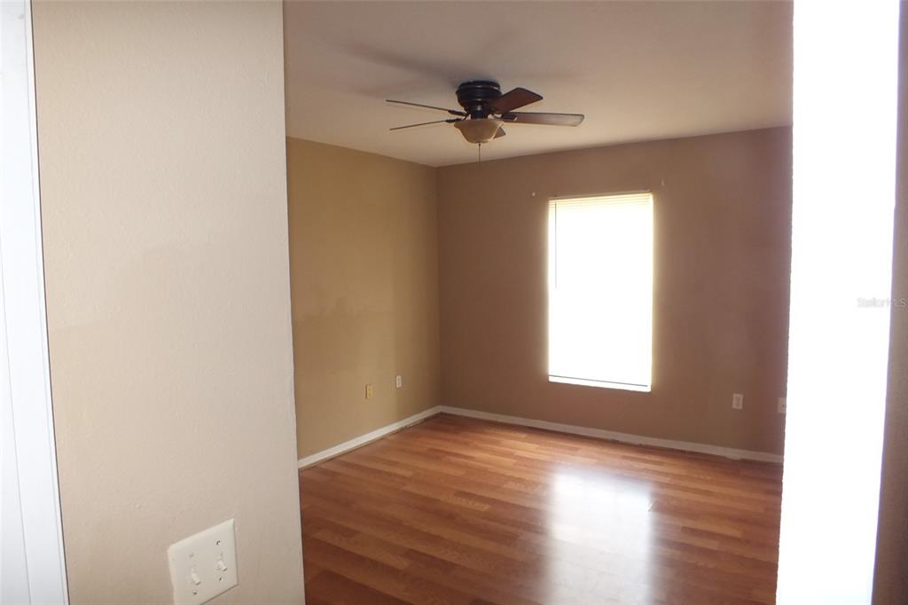 An empty room features light brown walls, wood-look flooring, and a ceiling fan — 437 FISH HAWK DRIVE, WINTER HAVEN, FL