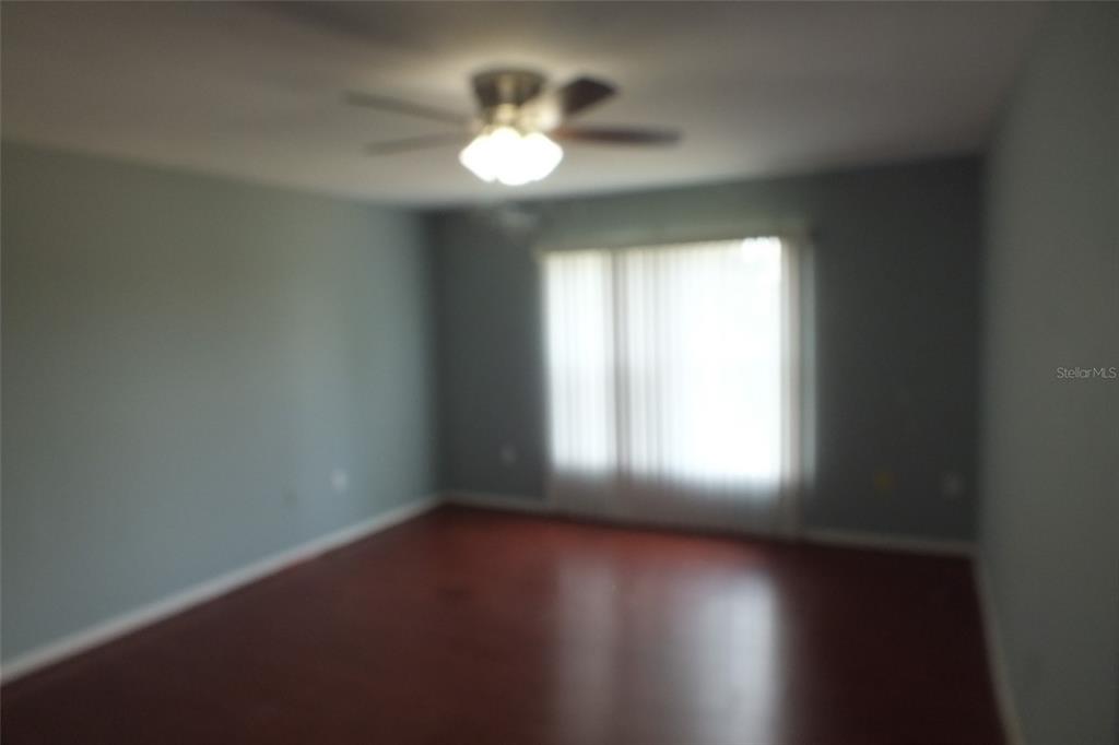 An empty room with light blue walls, dark wood-look flooring, and a ceiling fan — 437 FISH HAWK DRIVE, WINTER HAVEN, FL
