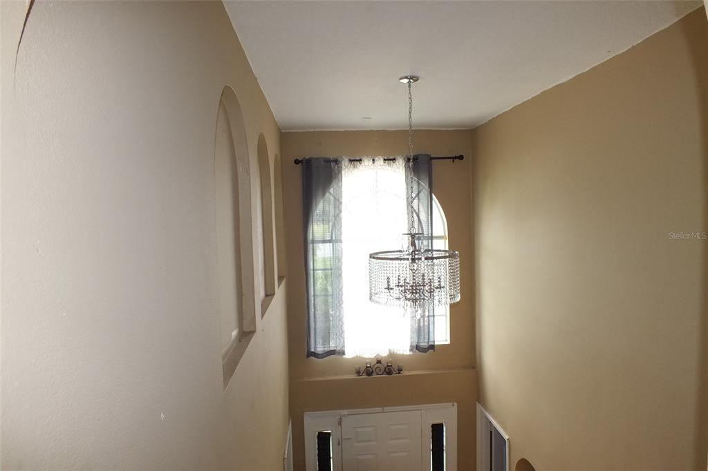 A high-ceilinged entryway features a crystal chandelier, arched wall niches, and a large window — 437 FISH HAWK DRIVE, WINTER HAVEN, FL