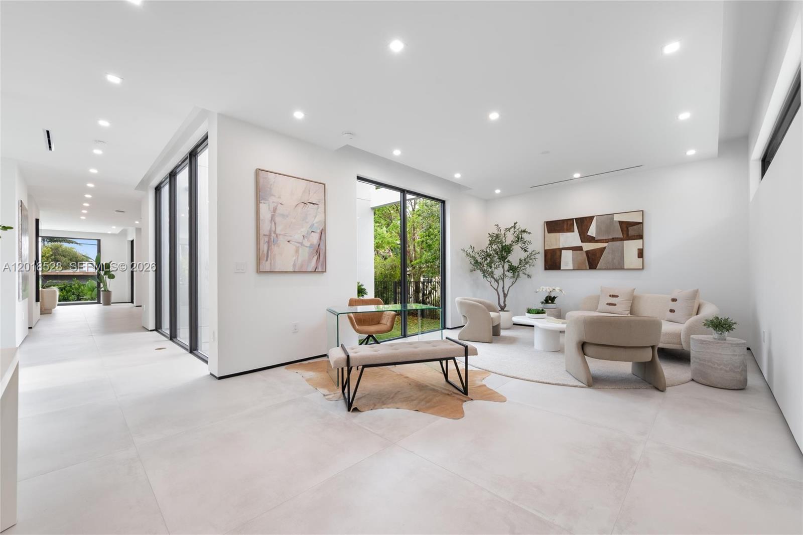 A bright, modern living room features white walls, large tile floors, and a glass desk — 2096 Alamanda Dr, North Miami FL 33181, NORTH MIAMI, FL