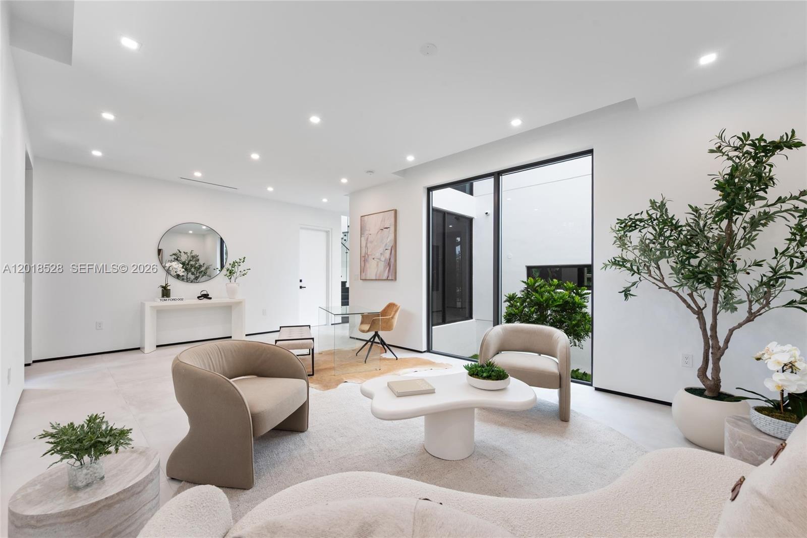 A modern living room features white walls, neutral furniture, a coffee table, and large windows — 2096 Alamanda Dr, North Miami FL 33181, NORTH MIAMI, FL