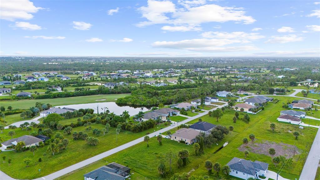 An aerial view shows a residential neighborhood with houses, a pond, and green lawns — 70 TEE VIEW ROAD, ROTONDA WEST, FL