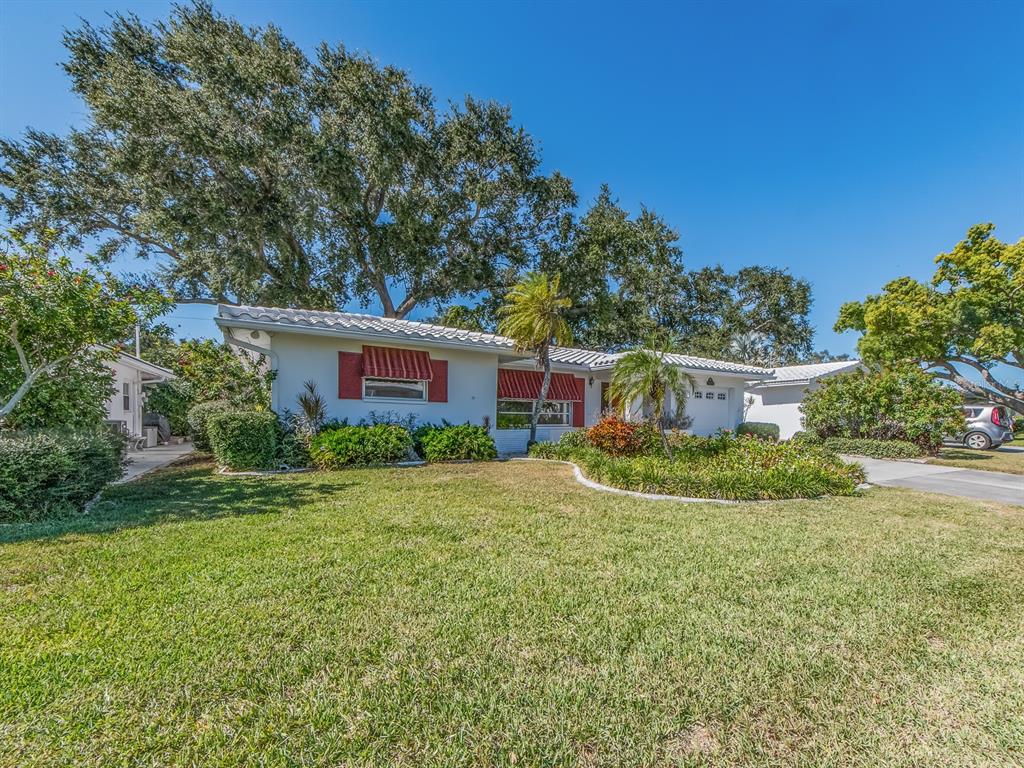 A single-story white house with red awnings and a large front lawn under blue skies — 9234 141ST STREET, SEMINOLE, FL