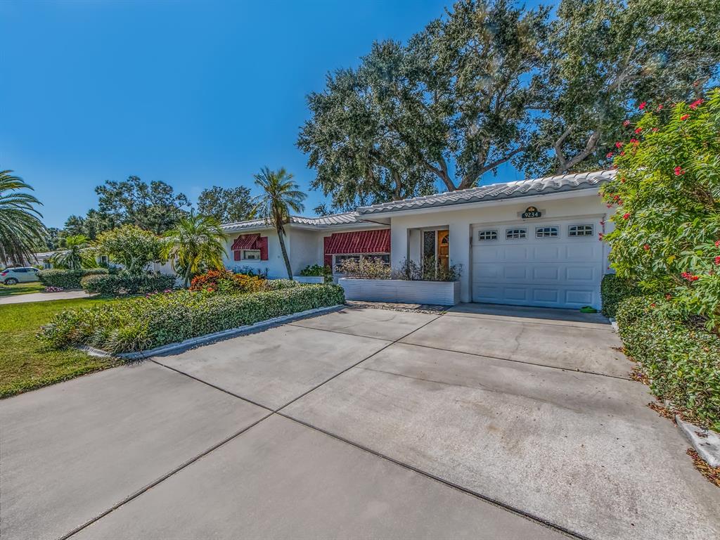 A single-story house with a white garage, red awnings, and a concrete driveway — 9234 141ST STREET, SEMINOLE, FL