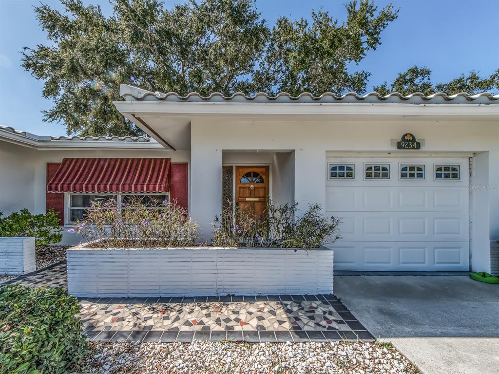 A white house exterior features a tiled roof, a mosaic walkway, and a single-car garage — 9234 141ST STREET, SEMINOLE, FL